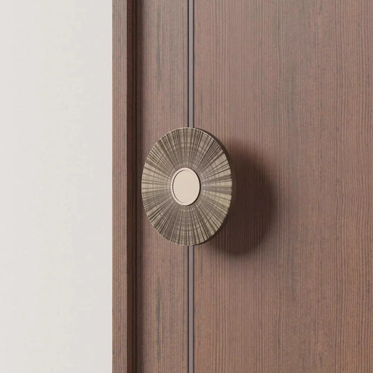 A close-up image of a door handle with a sunburst motif, featuring intricate radial etching.